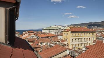 A cityscape with red-tiled roofs and a view of the sea.