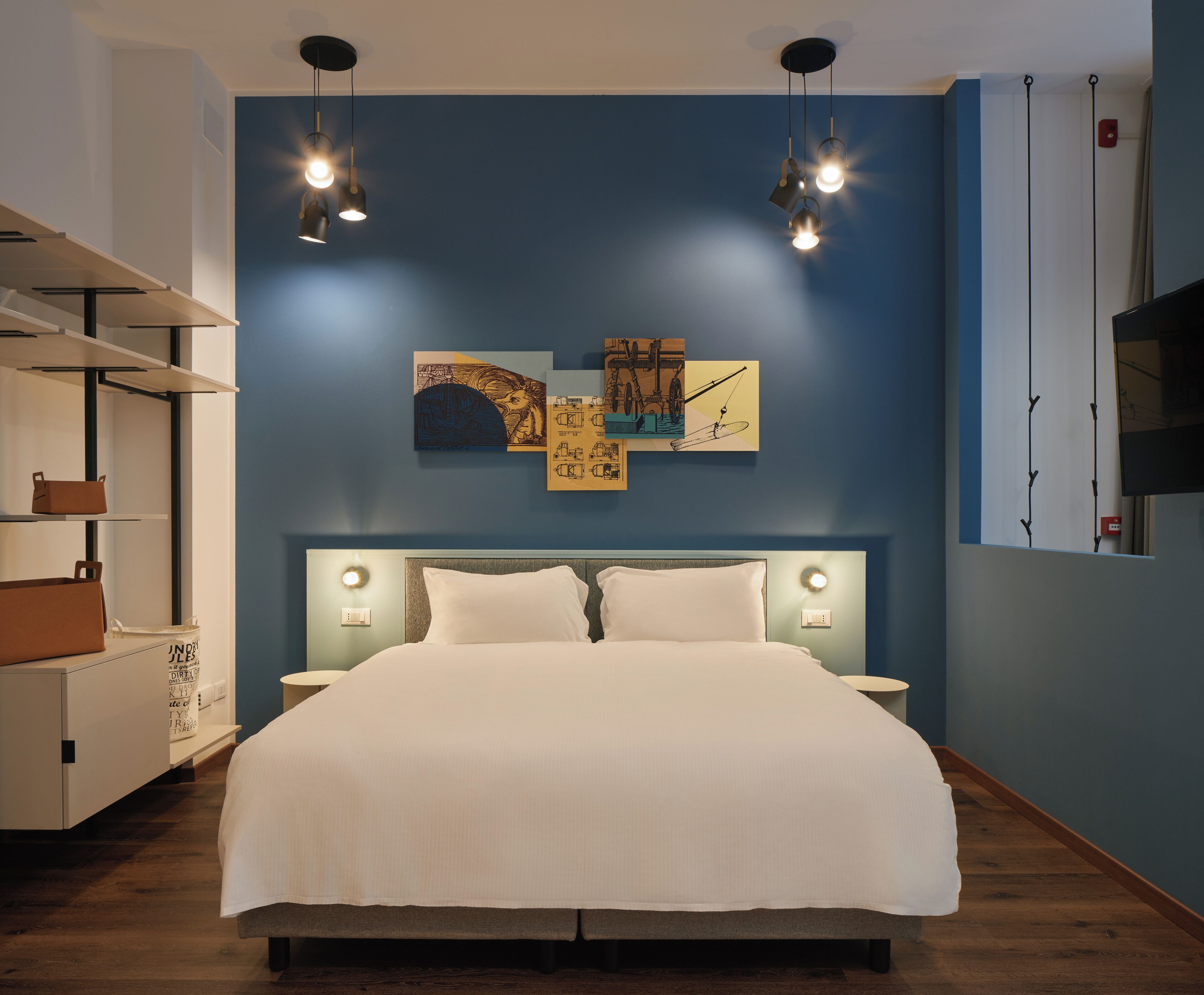 A bedroom with a bed, bedside tables, wall art, and a TV.