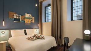 A hotel room with a bed, a desk, a chair, and artwork on the wall. - Urbanauts Studios Minelli (Trieste)