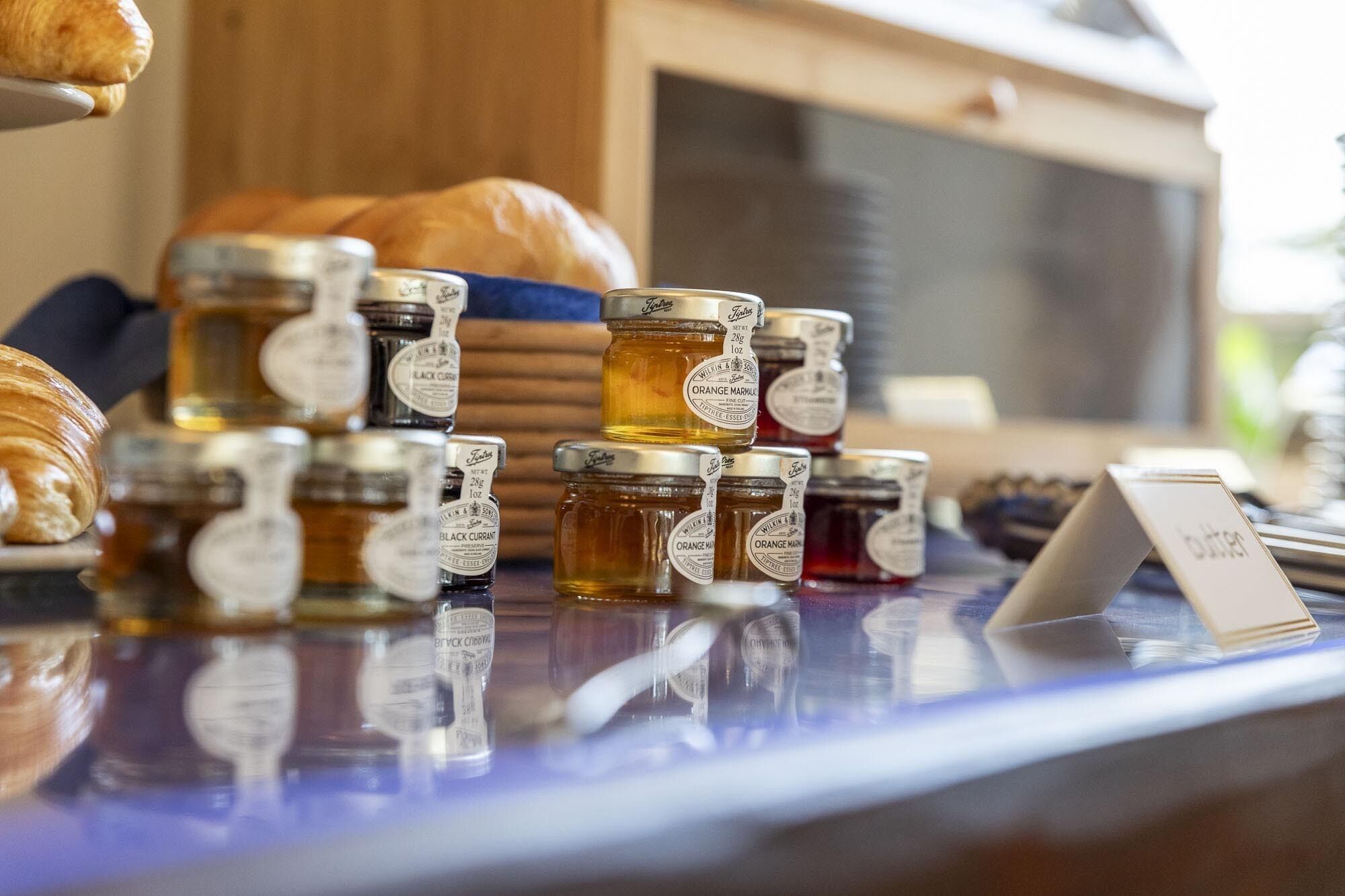 A selection of honey jars and a croissant on a counter.