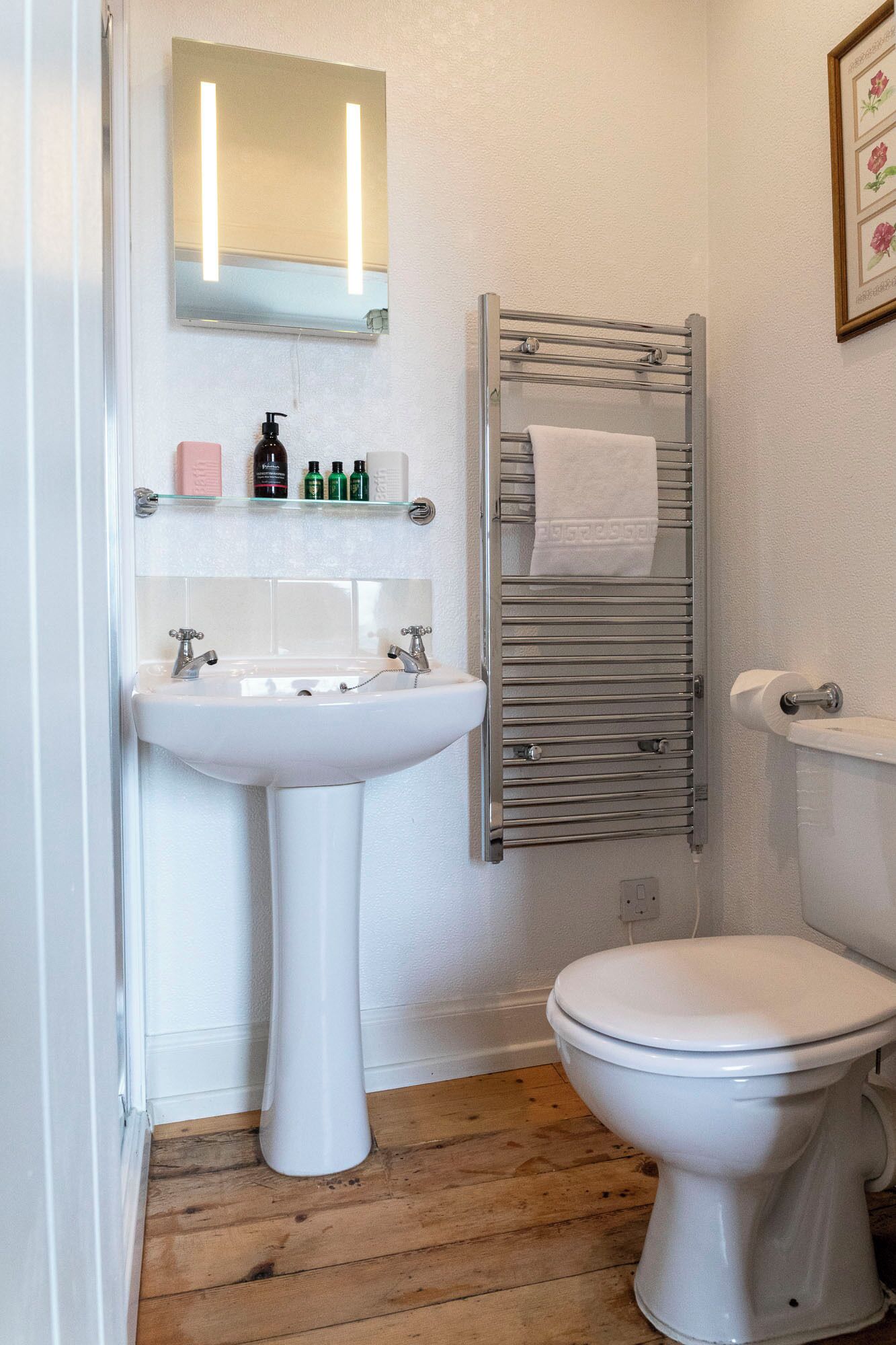 A bathroom with a white sink, a toilet, and a towel rack with a towel.