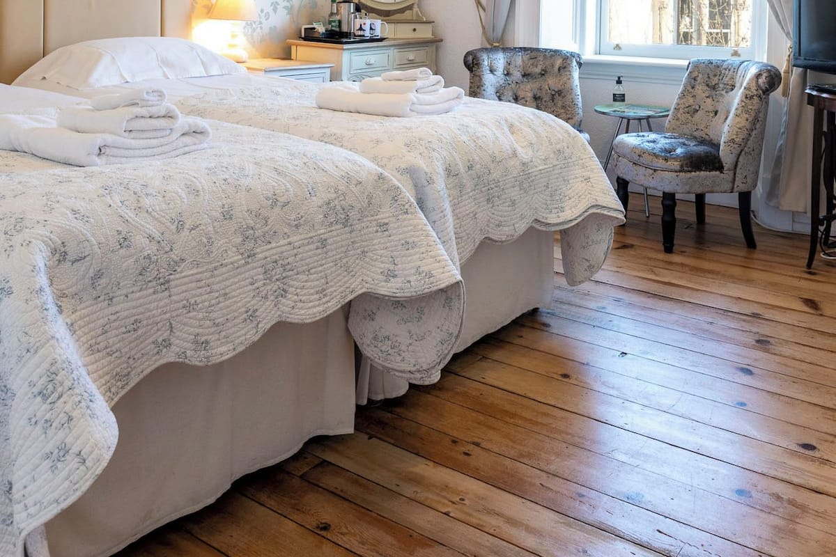 Una camera da letto con un letto grande, un comodino con una lampada, una sedia e vista all'esterno attraverso una finestra.