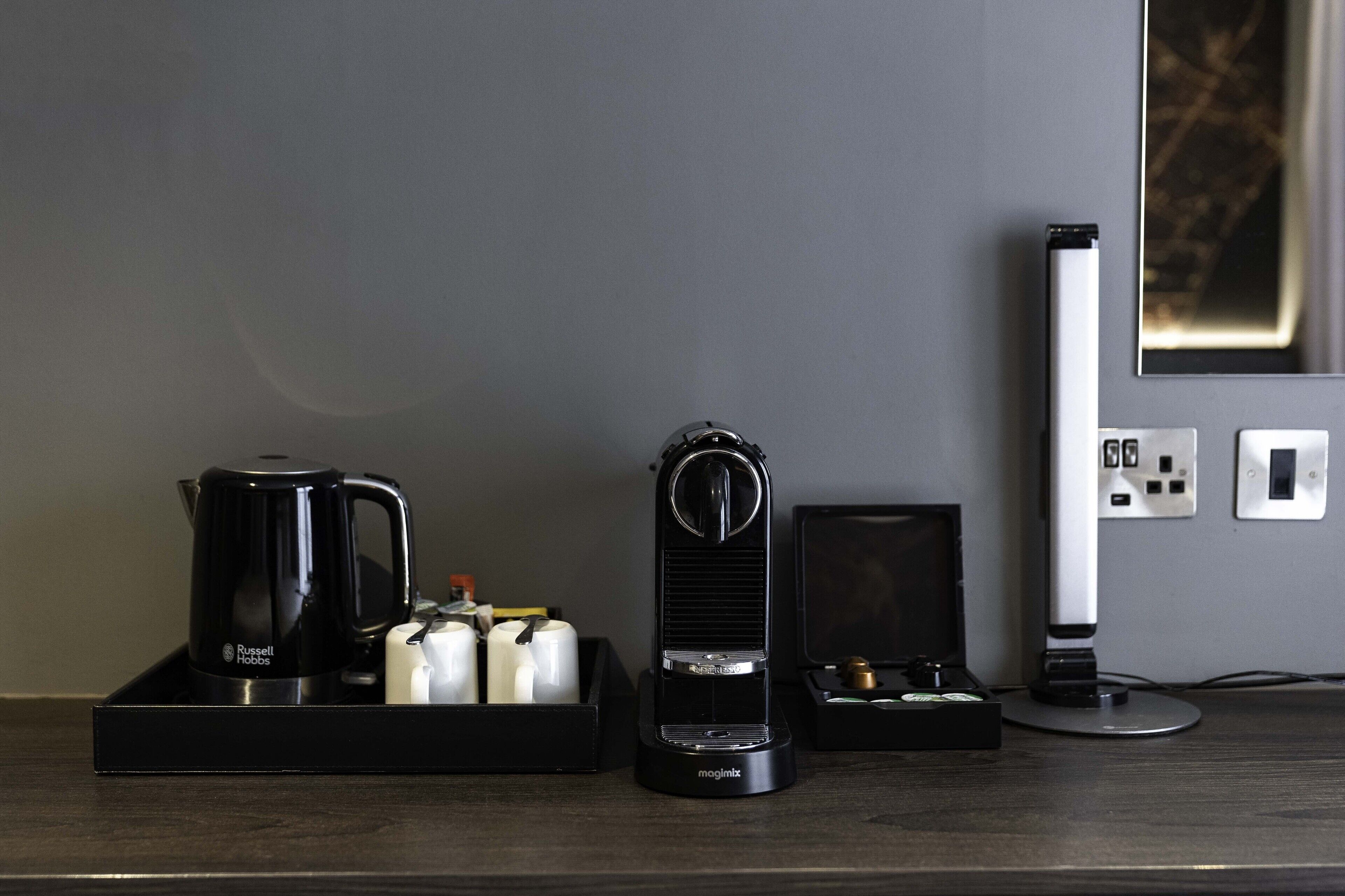 A coffee maker, a kettle, and a small box on a dark countertop.