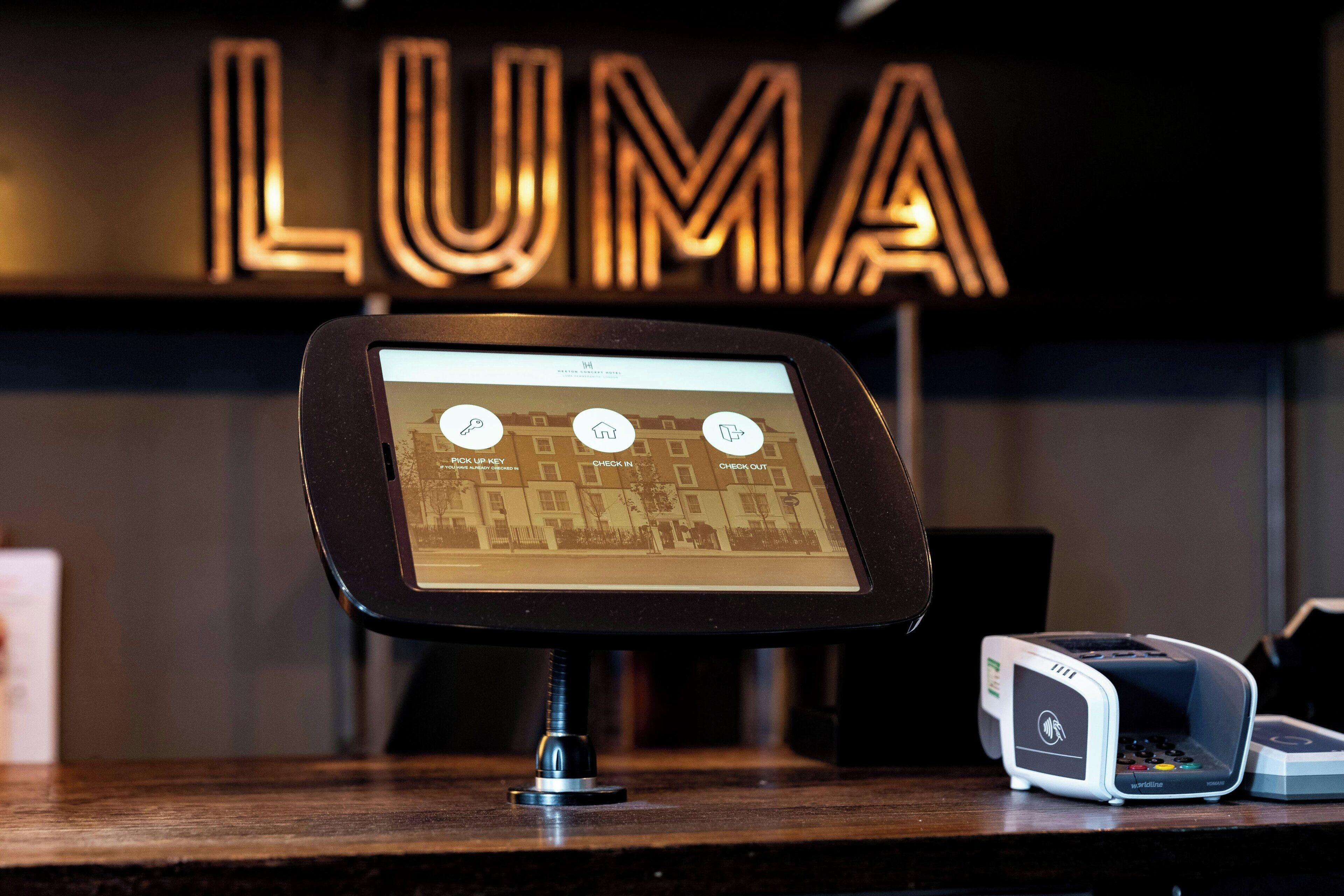 A digital kiosk with a map interface, a payment terminal, and a sign with the word 'LUMA' in the background.