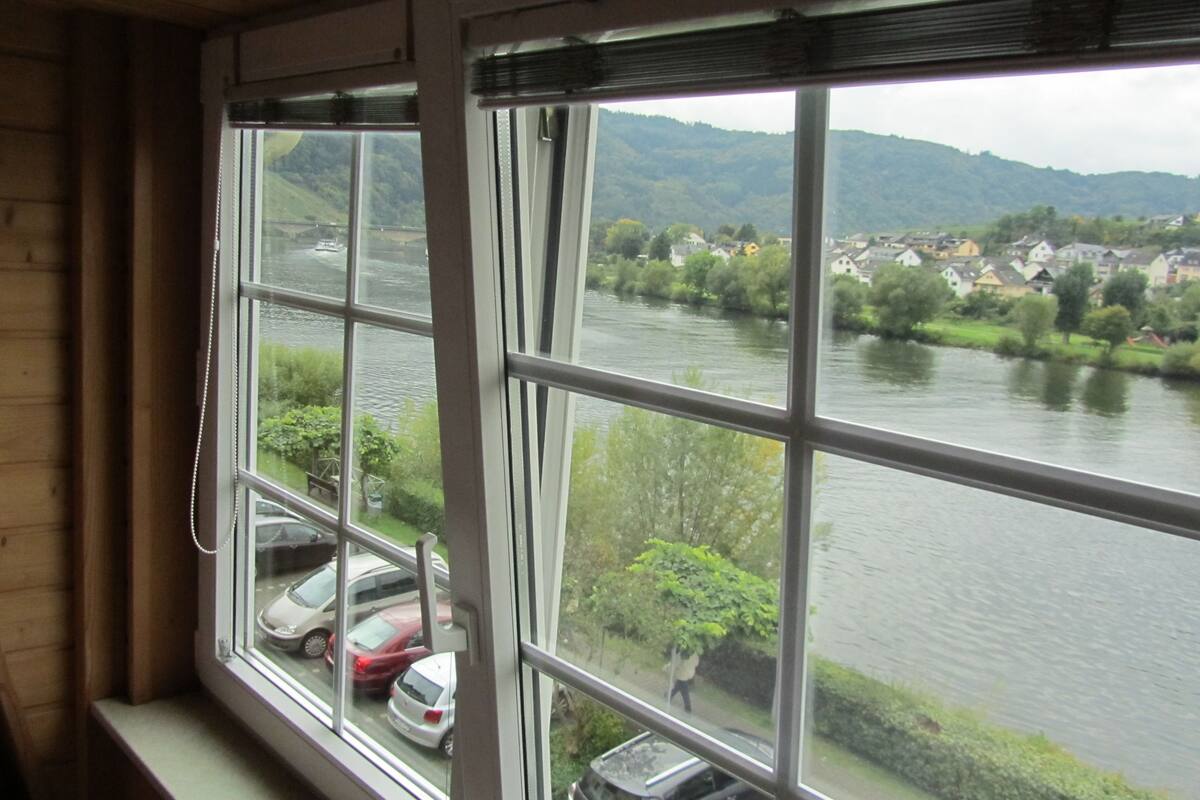 A view from a window overlooking a river with parked cars and a town in the background.
