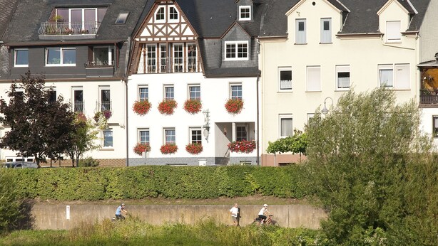 Eine Reihe traditioneller europäischer Gebäude mit Balkonen und Blumenkästen, gelegen am Flussufer.
