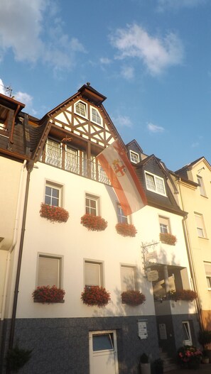 A building with a traditional architectural style, featuring a prominent flag and flower boxes on the facade. - Mosel Panorama (Zell (Mosel))