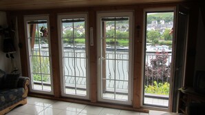 Ein Zimmer mit einer großen Schiebetür, die auf einen Balkon mit Blick auf einen Fluss und Häuser führt.