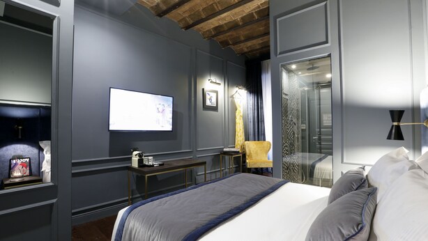 A modern hotel room with a large bed, a desk, a TV, and a bathroom visible through a glass door. - Saint B Boutique Hotel STB (Rome)