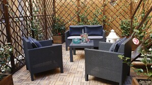 An outdoor patio with wicker furniture, a wooden floor, and a lattice fence. - Saint B Boutique Hotel STB (Rome)