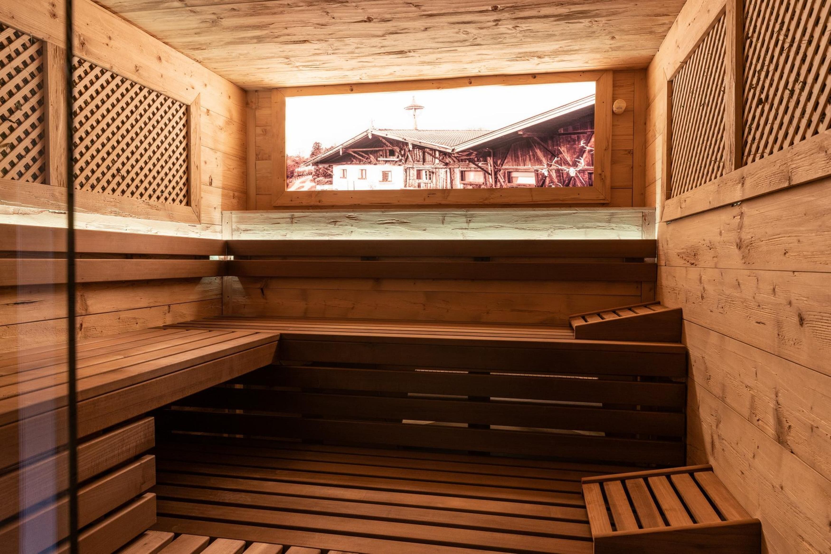 Eine Holzsauna mit Bänken und einem Fenster mit Blick auf ein traditionelles Gebäude.