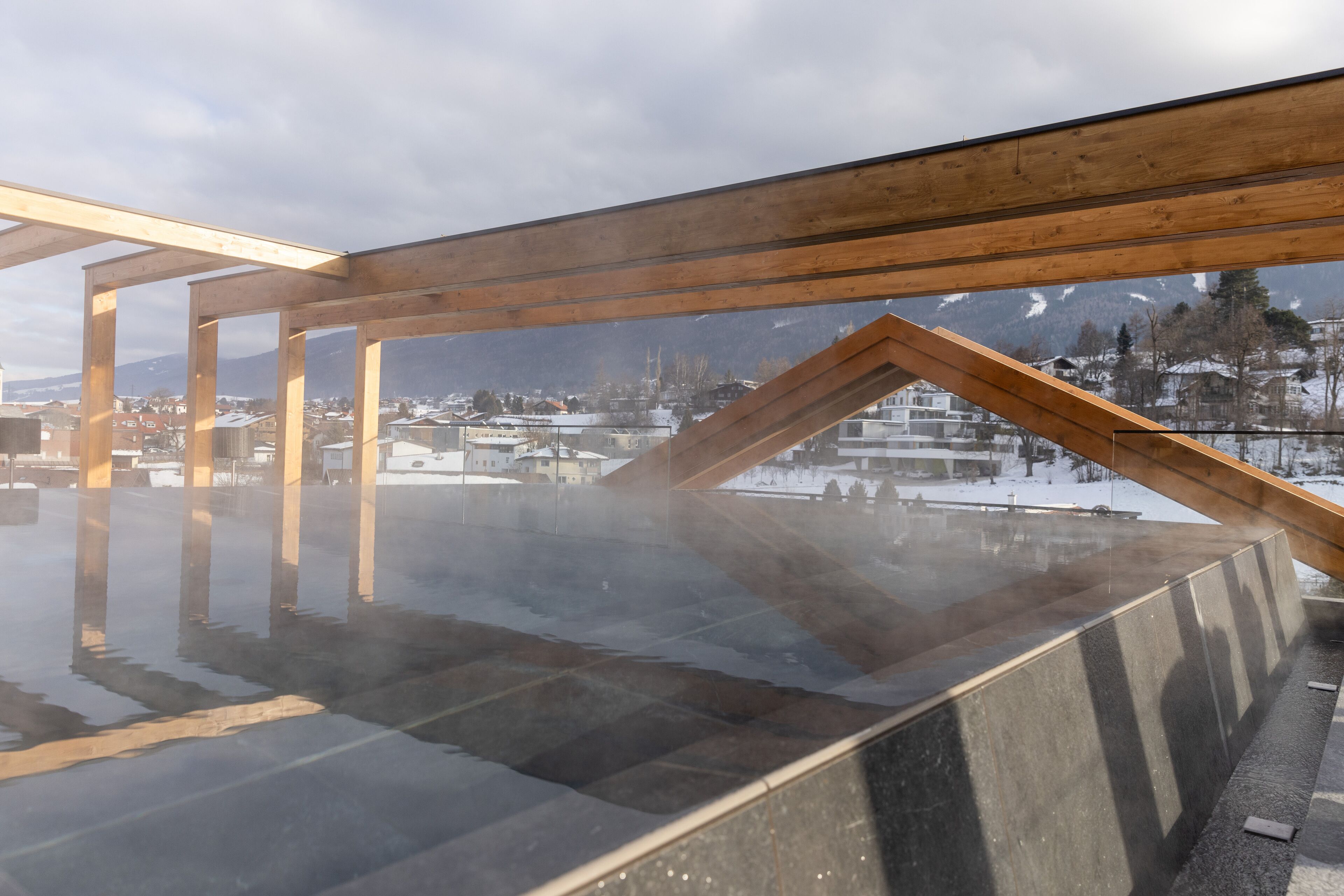 A sauna with a wooden roof structure and a view of a snowy landscape.