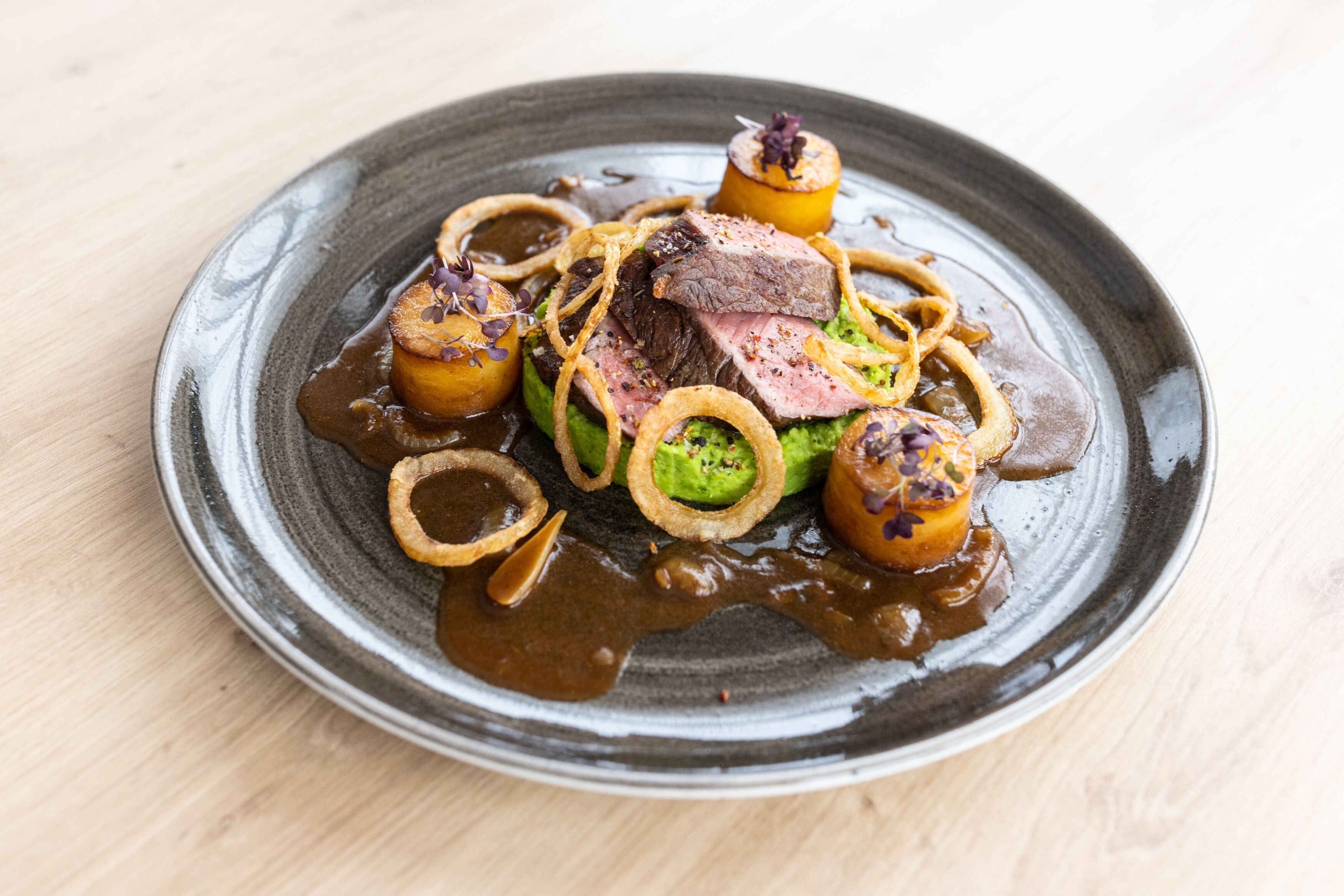 Ein Teller Essen mit Steak, Pilzen und Zwiebeln.