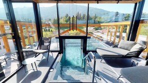 A modern balcony with a glass enclosure, a pool, and a view of a mountainous landscape. - Das Walzl (Lans)