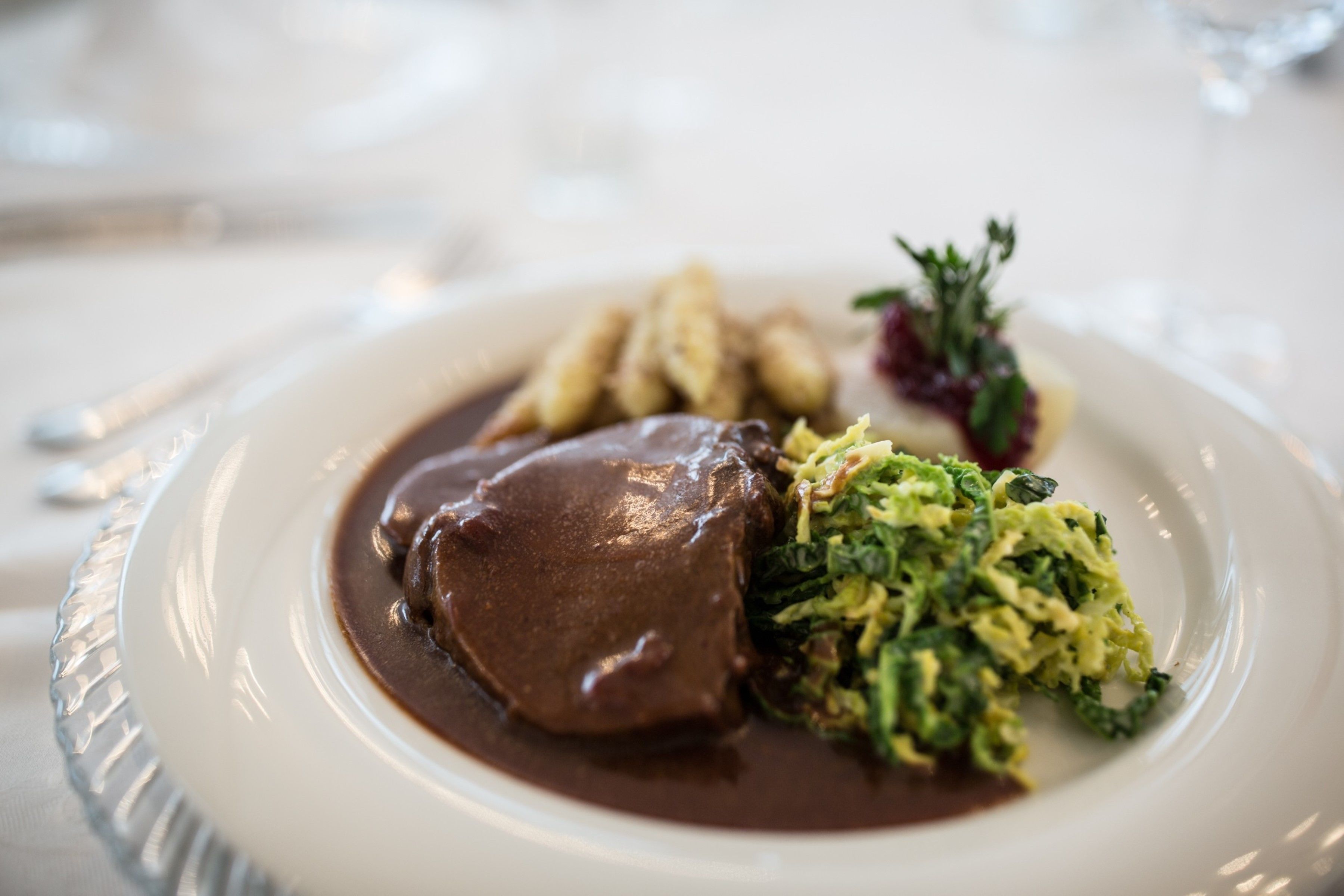 A plate of food with a meat dish, mashed potatoes, and greens.