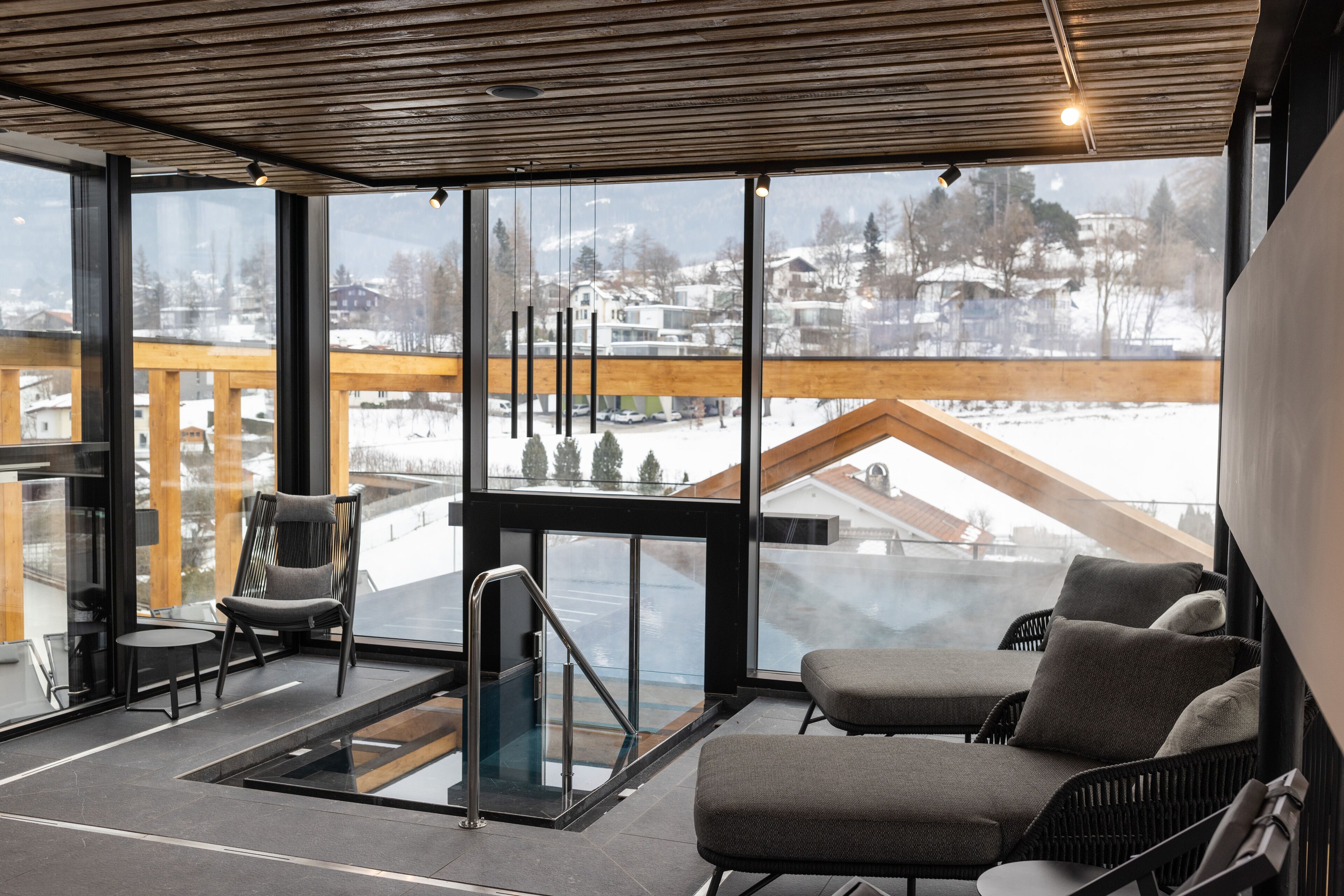 Ein modernes Interieur mit Glasgeländer, einer Sitzecke und Blick auf eine verschneite Landschaft.