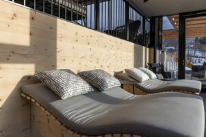 Quarto moderno com cabeceira de madeira, duas camas reclináveis com almofadas estampadas e uma grande janela com vista para o exterior.