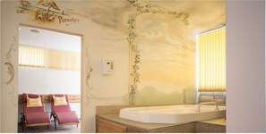 Une salle de bain dotée d’une grande baignoire, d’un meuble-lavabo et d’un espace dédié à un fauteuil de massage.