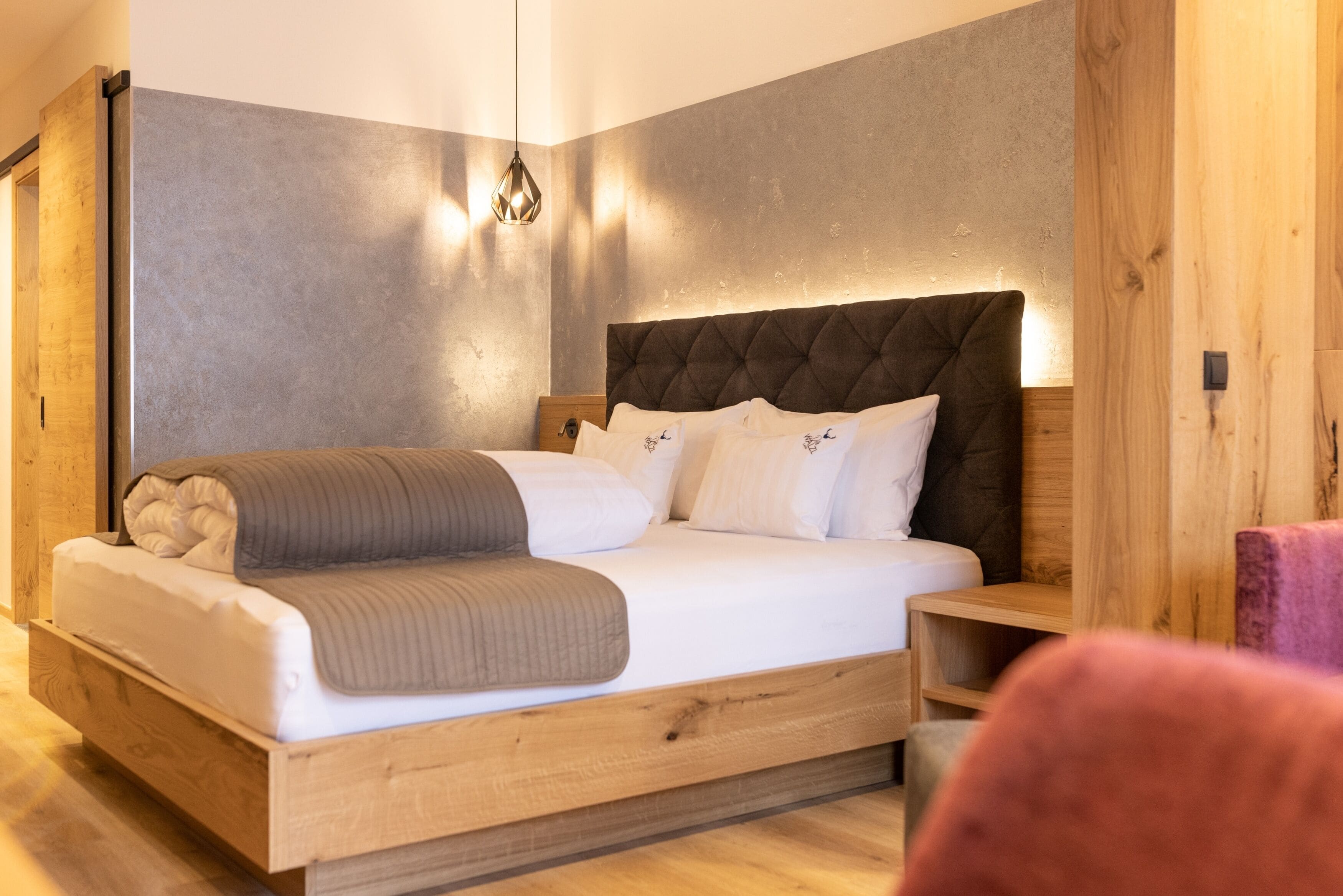 A modern bedroom with a wooden bed frame, a tufted headboard, and a bedside table.