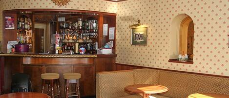 Zona de bar con taburetes, mostrador y pared decorada.