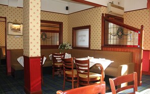 A restaurant with a traditional interior, featuring wooden chairs, a table, and patterned wallpaper. - Imperial Hotel (Castle Douglas)