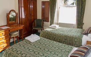 A room with two beds, a wooden dresser, a chair, a mirror, and a window with curtains. - Imperial Hotel (Castle Douglas)