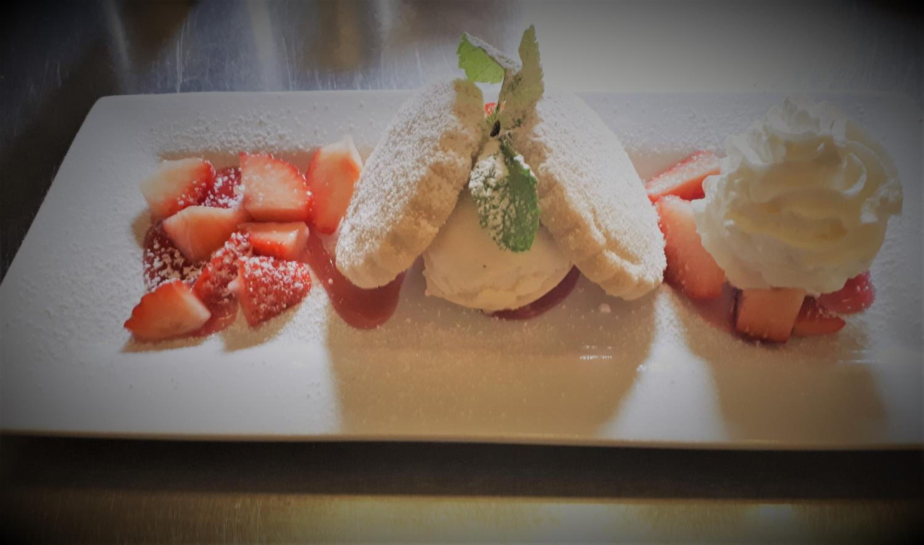 A dessert plate with strawberries, whipped cream, and a dusting of powdered sugar.