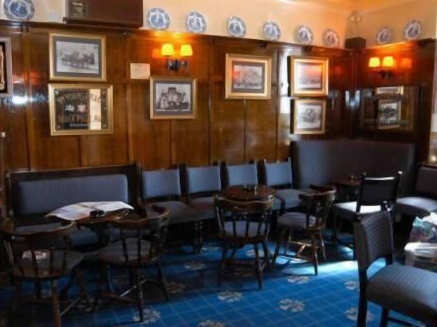 A restaurant with wooden paneling, framed pictures on the walls, and blue patterned flooring.