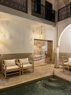 Ein Wellnessbereich mit Holzliegen, einem kleinen Pool und einer Steinwand.
