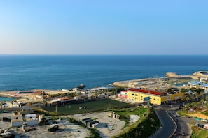 Eine Küstenstadt mit einem markanten gelben Gebäude, einer Straße und einer Strandbucht.