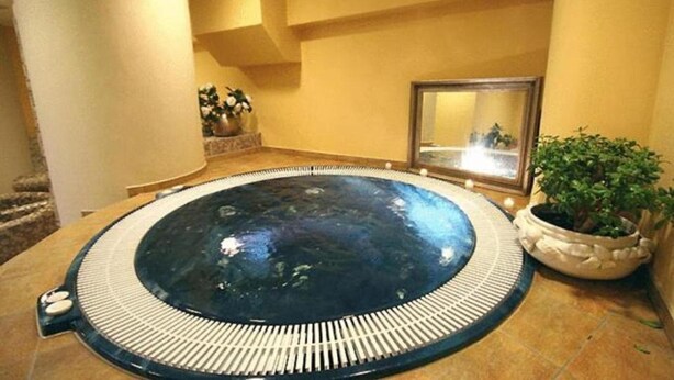 A spa area with a large circular hot tub, a mirror, and potted plants. - La Meridiana (Madesimo)
