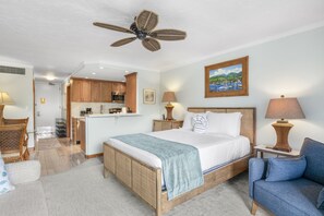 A hotel room with a bed, a desk, a chair, a kitchenette, and a ceiling fan. - Lahaina Shores #532 Studio Bedroom Condo by RedAwning (Lahaina)