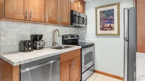 A kitchen with wooden cabinets, a microwave, a coffee maker, an oven, and a refrigerator. - Lahaina Shores #532 Studio Bedroom Condo by RedAwning (Lahaina)