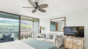 A hotel room with a bed, a sofa, a TV, a ceiling fan, a balcony with a view of the countryside, and a dining area. - Lahaina Shores #532 Studio Bedroom Condo by RedAwning (Lahaina)