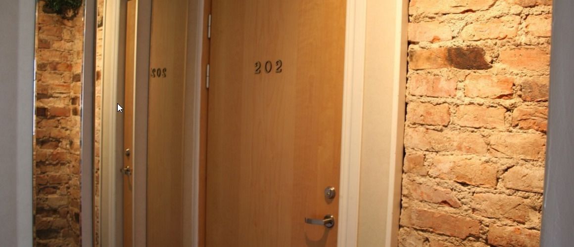 En dörr av trä med nummer 202, en mur av tegelstenar och ett handtag av metall.