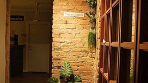 A stone wall with a sign reading "VALKOMMEN" and a wooden door with glass panels. - Hotell Östermalm (Motala)
