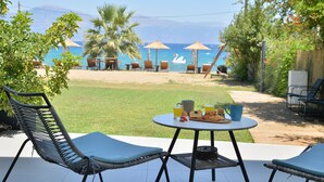 A patio with outdoor seating, a table with breakfast items, and a view of the beach and ocean.