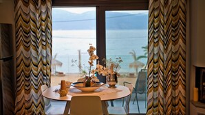 Uma área de refeições com uma mesa posta para dois, um vaso com flores e uma vela.