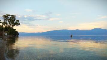 A calm lake with a boat in the distance, surrounded by mountains and trees.
