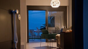 A modern room with a sliding glass door leading to a balcony, a green armchair, a small round table, and a lamp.