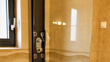 A modern bathroom with a glass-enclosed shower, a toilet, and a window.