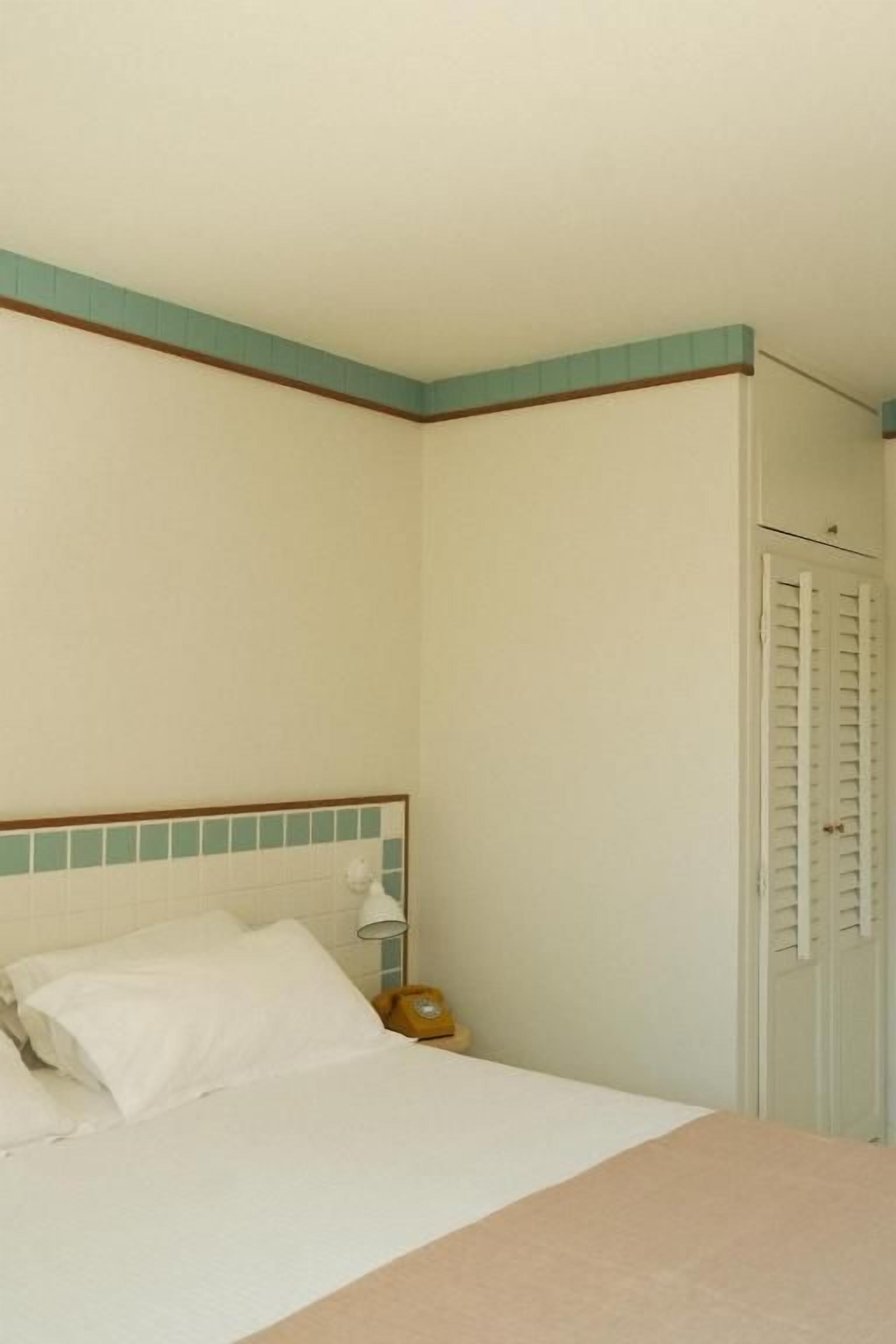Une chambre d’hôtel standard, comprenant un lit, une table de chevet, une lampe et une armoire.