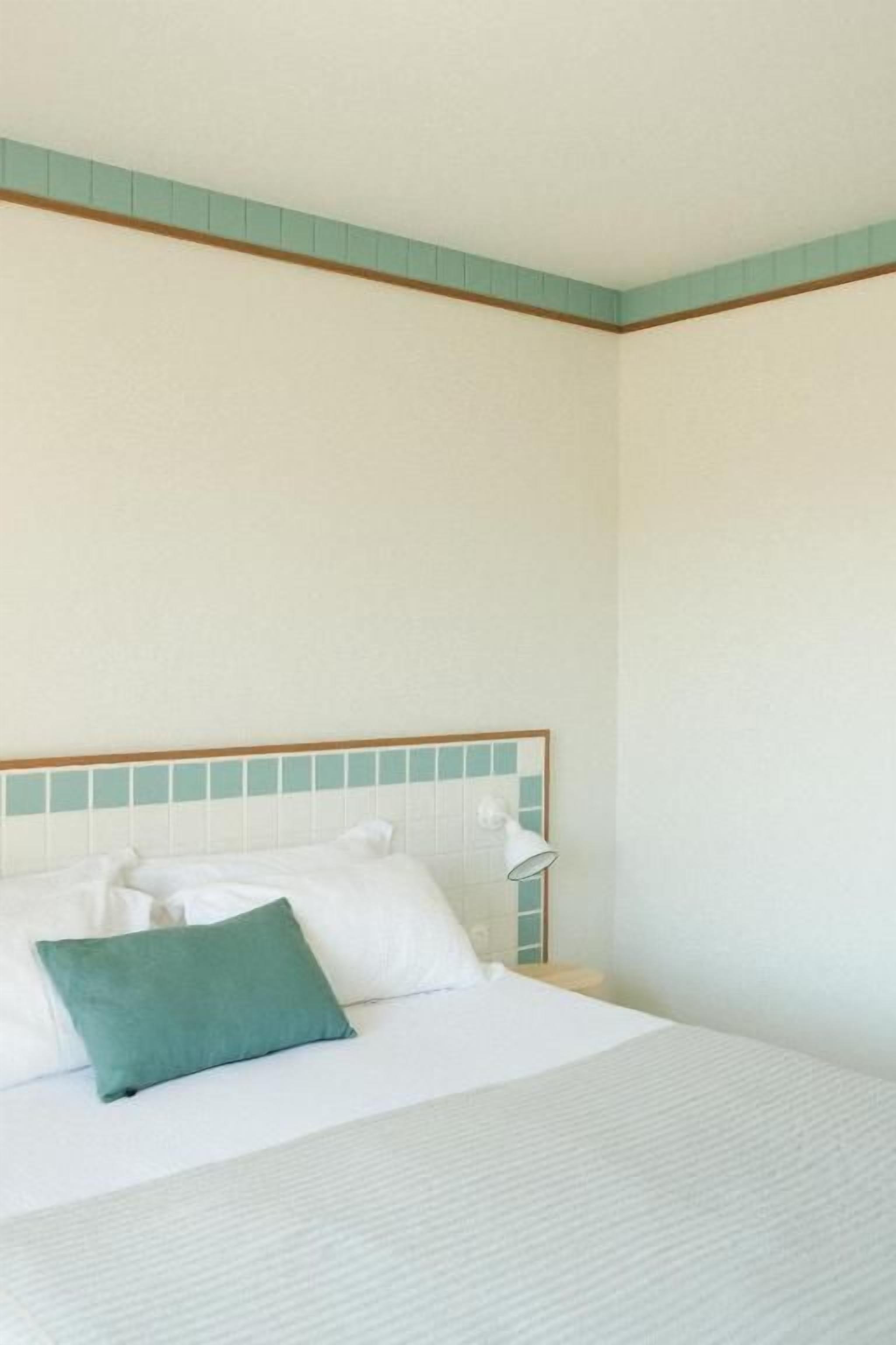 Habitació d'hotel amb llit, almoinades, una taula de nit i una làmpada.