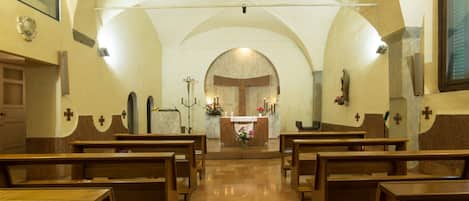 A church interior with pews arranged in rows, a central altar, and a vaulted ceiling.