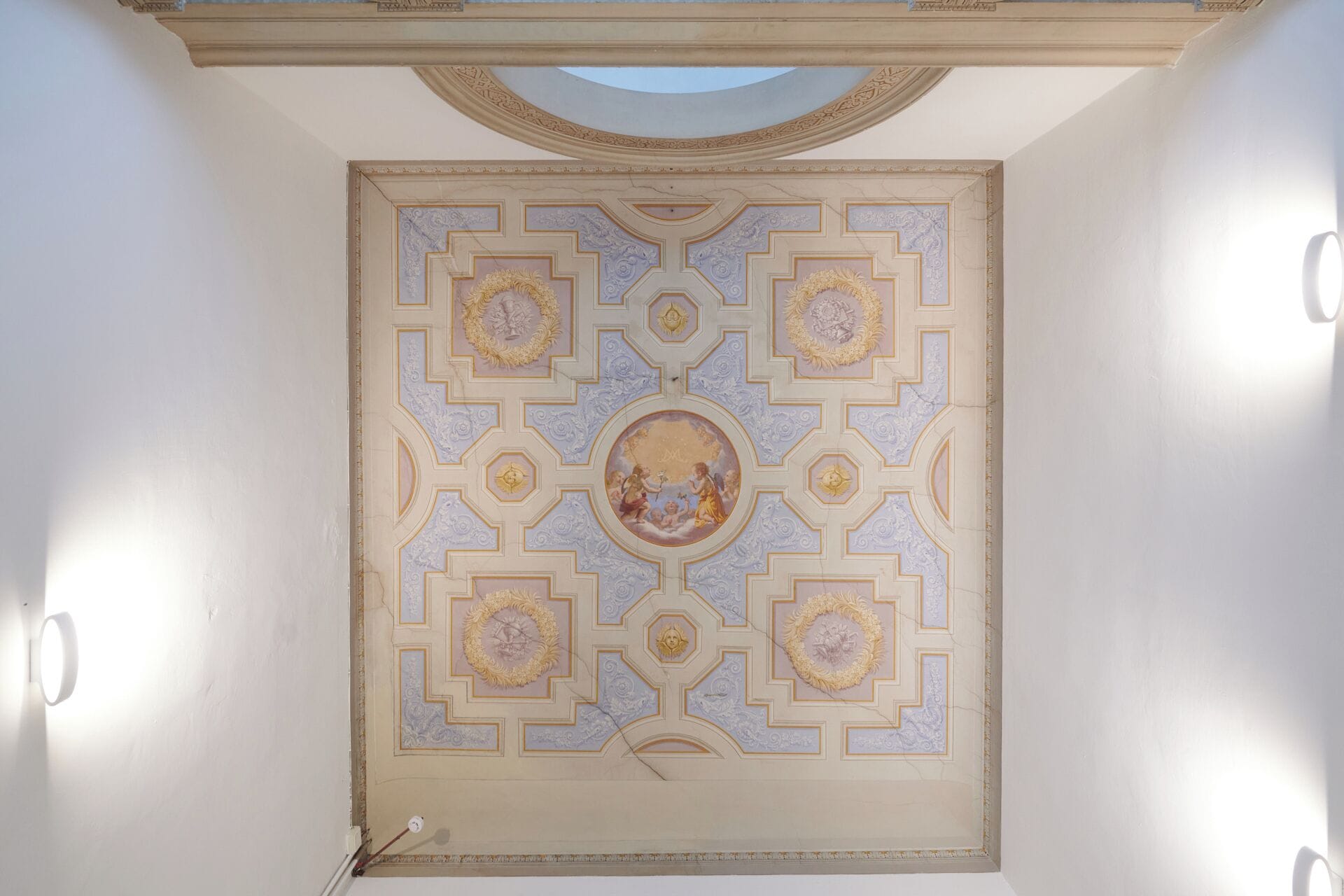 A ceiling with a geometric pattern and a central circular medallion.