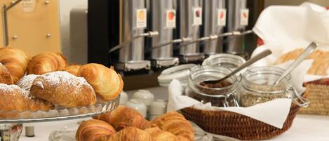 A buffet with pastries, including croissants and other baked goods, and a coffee station with multiple coffee dispensers.
