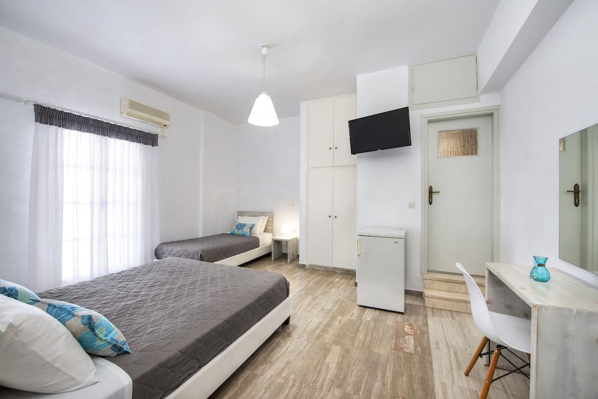 A bedroom with two beds, a desk, a TV, and a wardrobe.