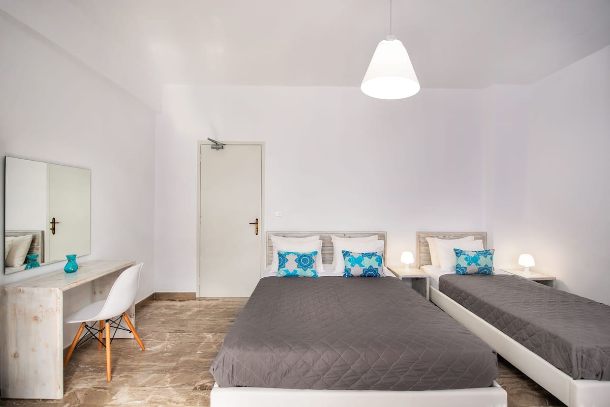 A bedroom with two beds, a desk, and a chair.