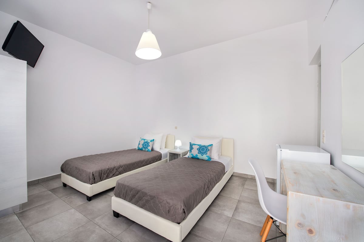 A modern bedroom with two beds, a desk, and a chair.