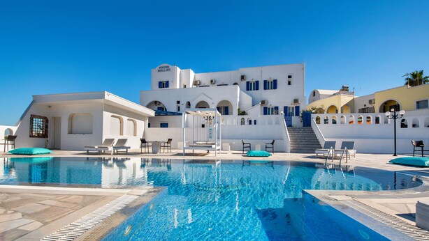 Una piscina blava cristal·lina amb gandules i un edifici al fons.